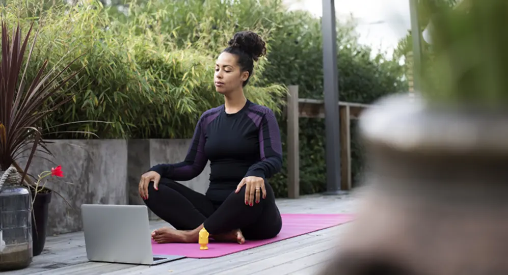 woman doing yoga, on laptop outside